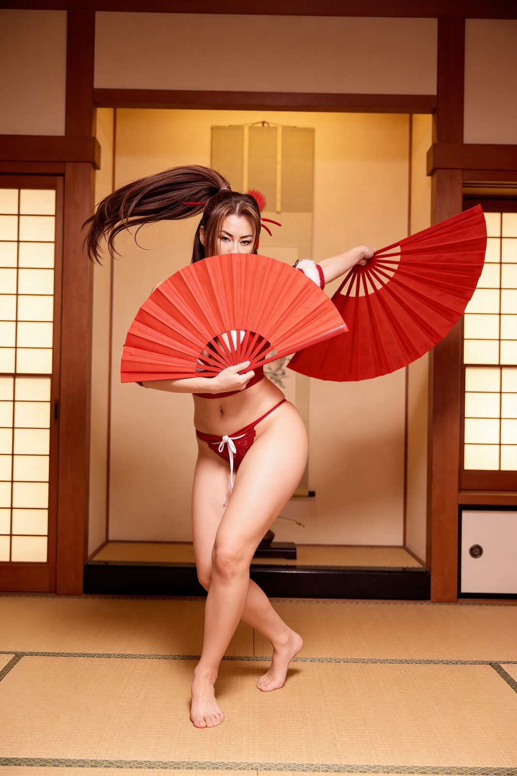 The fans, the red, the stance — the cosplay that made her name. At twelve the other kids started calling her Mai-chan for the coincidence of the name and the obsession; instead of shrinking, she owned it completely. At twenty-one the character carried her to a national cosplay title. “I’m not cosplaying a character,” she says. “I’m channeling her spirit.”