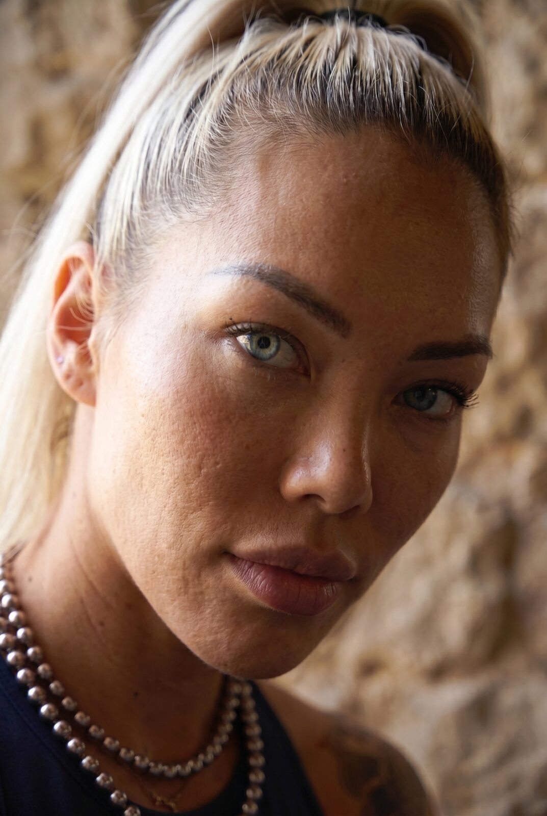 No filter, no performance — freckles, a fine scar, grey-green eyes that read a bell the way most people read a face. “The tower always tells you who’s faking.” She has never once needed to.